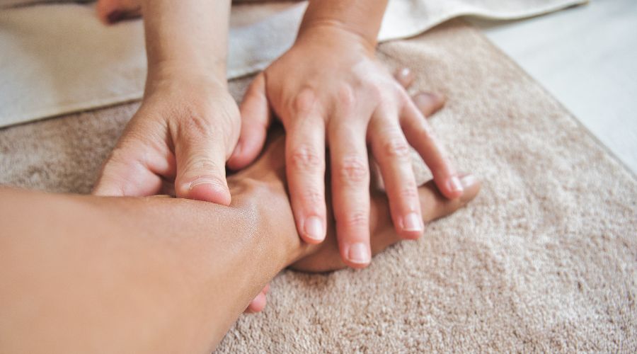 A massage therapist massages someone's hand