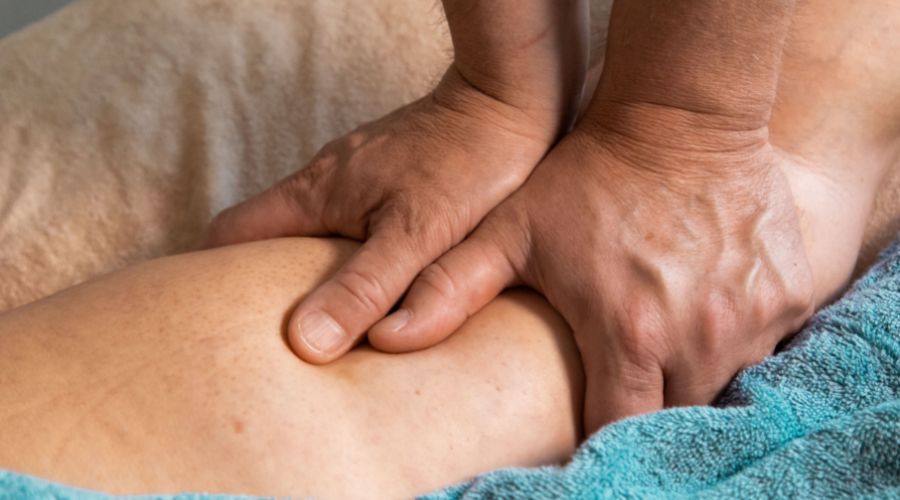 A massage therapist applying pressure to someone's leg.